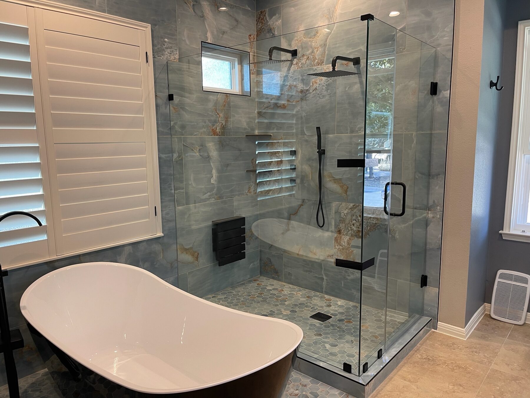 Custom frameless corner shower enclosure beside a freestanding tub